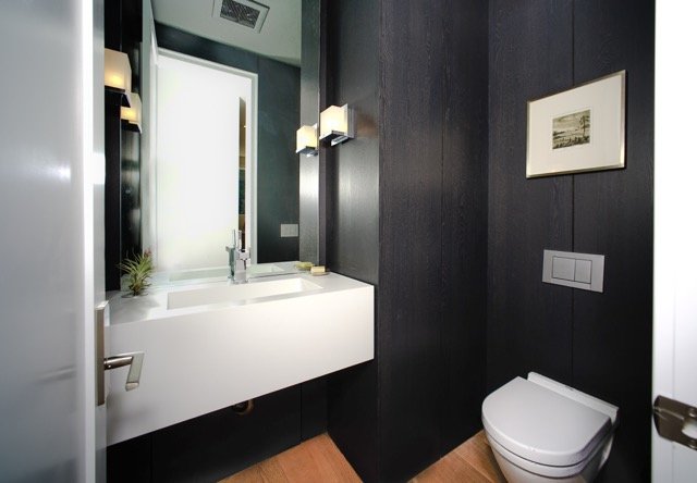 Powder room with a dark wood wall and a floating white basin